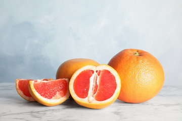 Fresh tasty grapefruits on table against color background