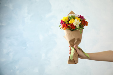 Woman holding bouquet of beautiful spring freesia flowers on color background. Space for text