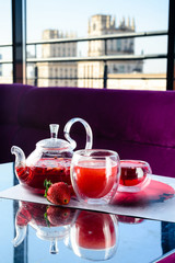 red tea with strawberries in a glass teapot in a cafe