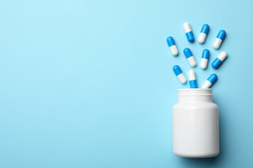 Bottle with pills on color background, flat lay. Space for text