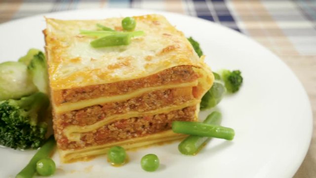 Italian food. Close-up shot of meat lasagna on a white plate. Slow motion. HD