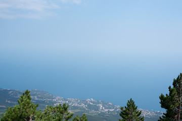 Fototapeta na wymiar The sea and the city from the mountains from the bird's eye view of the beautiful blue sea of water reflecting the clouds on the background of green mountains and South of the city 