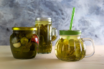 Cucumber pickle in a jar with a lid and tube on wooden table. Close-up