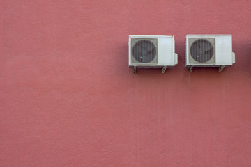 two white air conditioner radiators on a red granular concrete wall. rough surface texture