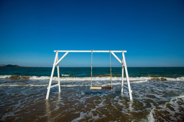 a white swing on the beach