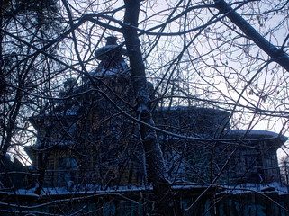 old wooden house behind the fence in winter