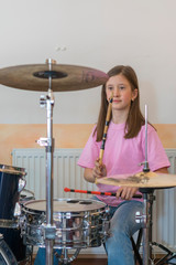 Little caucasian girl drummer playing the elettronic drum kit and shuoting. Teen girls are having...