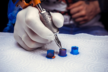 Hand of a professional tattooist with a tattoo machine.