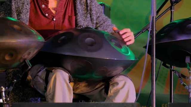 Man playing tank drum or hang on stage of ethnic open air concert. Relaxation, folk, meditative and traditional ethnic music concept