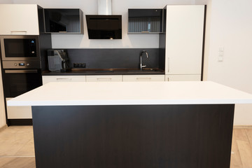 Modern new light interior of kitchen with white and black furniture