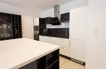 Modern new light interior of kitchen with white and black furniture