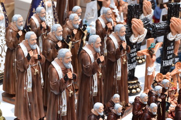 Fototapeta na wymiar Miniature statues of Saint Father Pio are displayed for sale on church yard during Lenten Week