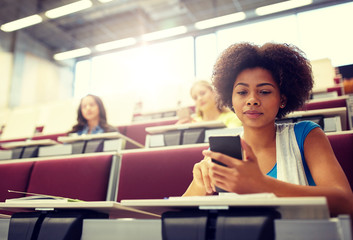 education, high school, university, learning and people concept - african student girl with smartphone at lecture