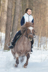 A young woman riding a brown horse on a snowy ground