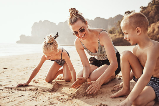Mother and her children playing together on a sandy beach