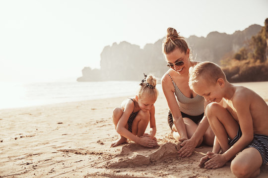 Mother and her cute kids playing on a sandy beach