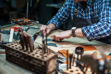 Man working with leather textile at a workshop.