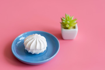 Fototapeta na wymiar White cake in a blue plate on a pink background
