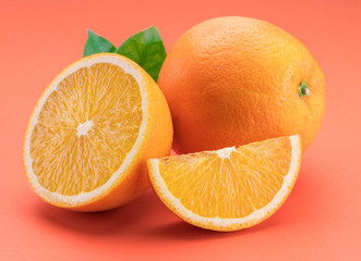 Orange fruit with orange slices and leaves isolated on orange background.