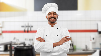 cooking, profession and people concept - happy male indian chef in toque with crossed arms over...