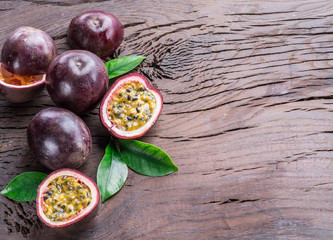 Passion fruits and its cross section with pulpy juice filled with seeds. Wooden background.