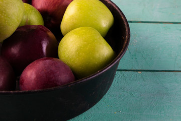 Apples in an vintage iron plate on a wooden background. Side view