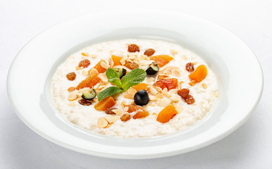 Oatmeal breakfast with raisins, dried apricots and peanuts on white background