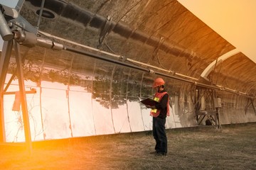 The worker in uniform and helmet checks Solar Parabolic Troughs.