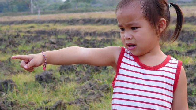 Asian little girl is crying on the ridge of land, cracked and dried in the field.