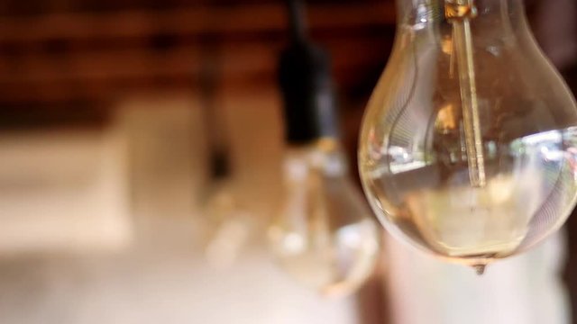 Close up view of Light bulb hanging on wooden ceiling in coffee cafe. Select focus.