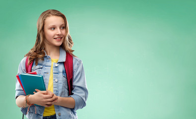 education, school and people concept - happy smiling teenage student girl with bag and books over green chalk board background