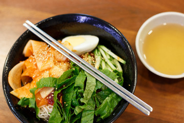 Korean noodles in a bowl on a wooden table close-up, top view.