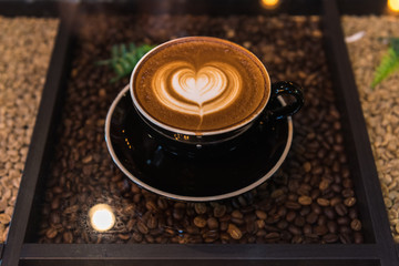 A cup of latte art coffee on table with coffee beans backgrounds