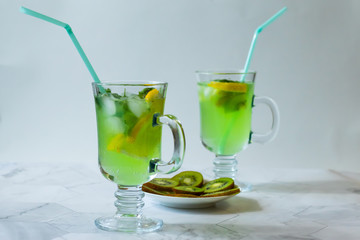 Refreshing lemonade from kiwi and lemon with ice on a light background. Horizontal orientation