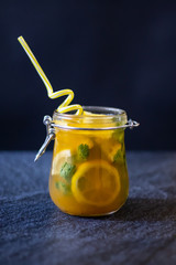 Freshly squeezed orange juice with pulp, kiwi and lemon on a dark background. Vertical orientation