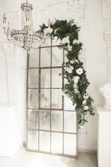 Beautiful vintage mirror stands on the floor on top of flowers