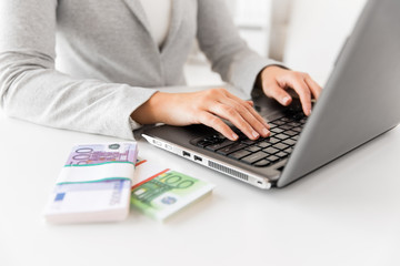 business, internet earning and technology concept - close up of businesswoman with laptop computer...