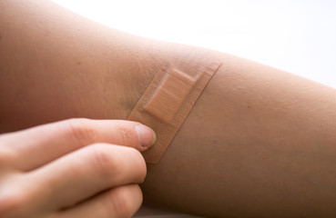 woman removing adhesive plaster off injury after blood test injection