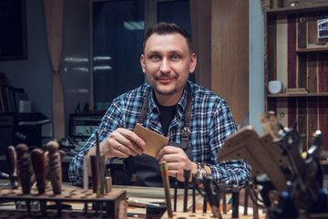 Man working with leather textile at a workshop. Concept of handmade craft production of leather goods.