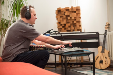 Musician playing djembe drum instrument in home music studio.