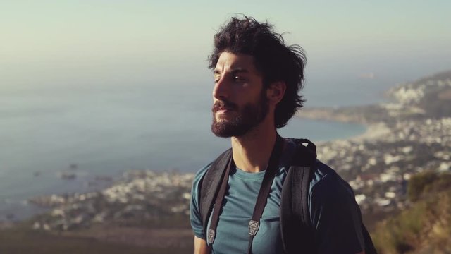 Hiker Shielding Eyes While Standing On Mountain Against Sky