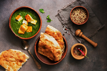 Palak paneer or Spinach and Cottage cheese curry,mortar with spices , naan, rice on a dark background. Traditional Indian dish. Top view, copy space.