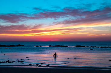 Outline of person meditating in yoga position in the sea at twilight