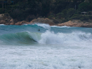 Olas rompiendo en la playa y surfistas esperando la Ola para cabalgarla