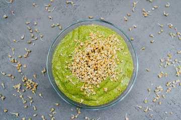 Top view of green smoothie dish in bowl with green buckwheat sprouts. Healthy breakfast. Vegetable dish. Meal full of vitamins. Super bowl