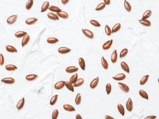 Flax seeds pattern. Brown flax seed on white concrete textured background. Top view or flat lay. Healthy food and diet concept