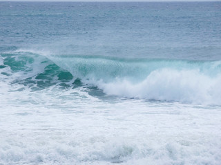 Naklejka na ściany i meble Olas rompiendo en la playa y surfistas esperando la Ola para cabalgarla