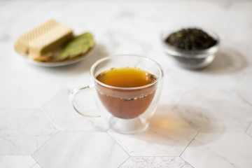 Green tea with jasmine in a transparent mug on a light background. Horizontal orientation