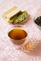 Green tea with jasmine in a transparent mug on a light background. Vertical orientation