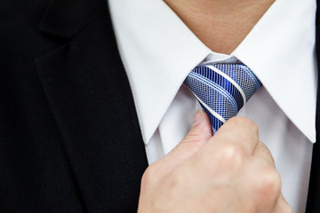 Smart business man adjusting a neck tie close up.